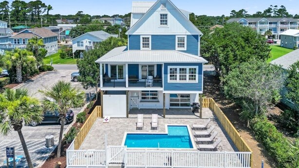 A two-story house with a swimming pool and a fenced deck area. - Epic 7BR Getaway - Pool, Game Room, Put-put, Beach (North Myrtle Beach)