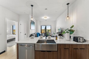 Cozinha moderna com ilha central, eletrodomésticos de aço inoxidável e iluminação pendente.