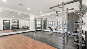 A modern gym with mirrored walls, a variety of weightlifting equipment, and a wooden floor. - Luxury 2bd/2ba near Boston sly2 (Everett)