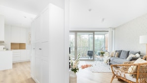 Een moderne woonruimte met een keuken, eethoek en zithoek met een bank en een rieten stoel.