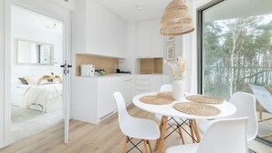 Een moderne, open woon- en eetruimte met een groot raam met uitzicht op een bos.