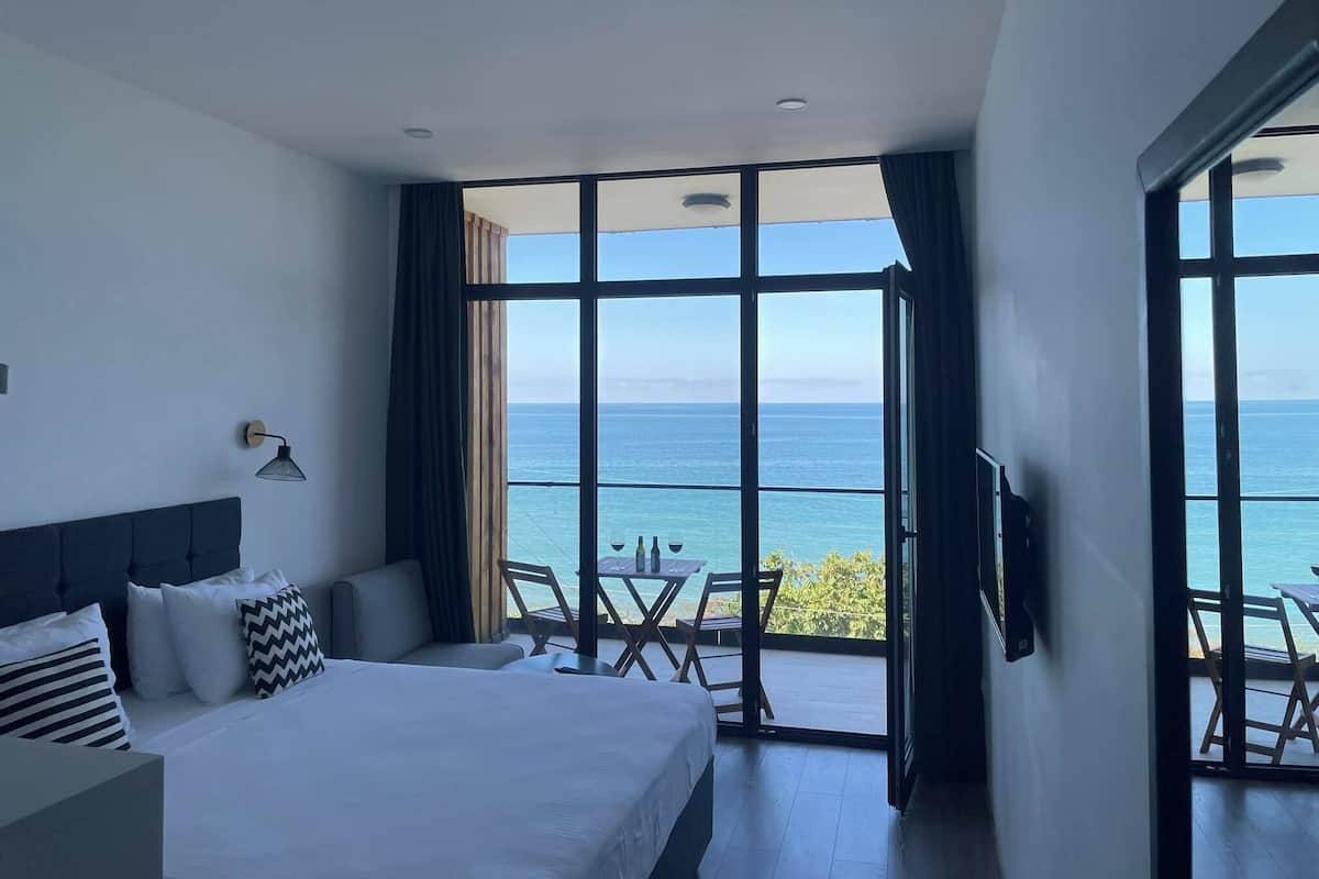Habitación de hotel con una cama grande, un escritorio y vista al mar.