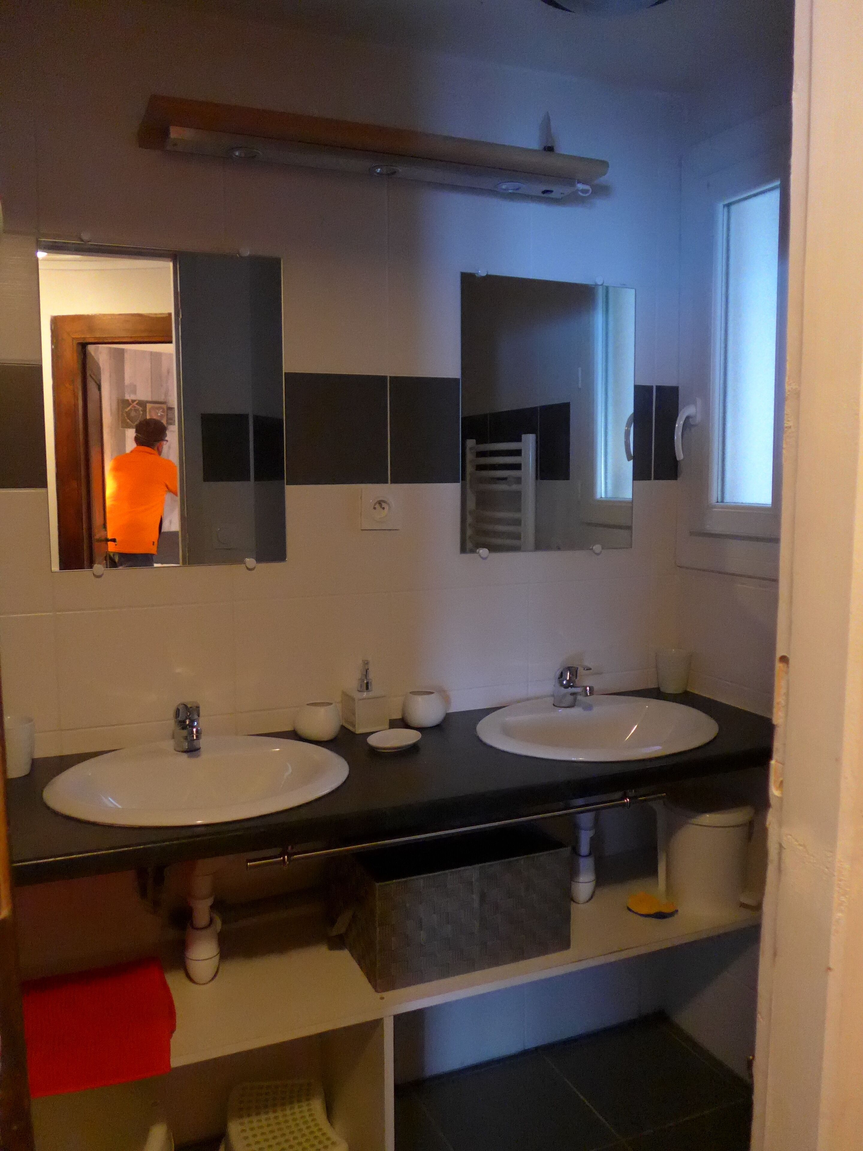 Een badkamer met twee wasbakken, een spiegel en een handdoekrek.