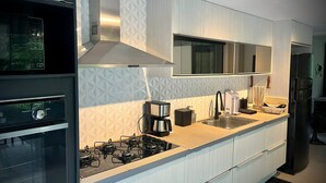 Een moderne keuken met een gasfornuis, roestvrijstalen apparatuur en een groot raam boven de gootsteen.