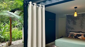 Een slaapkamer met een bed, een hanglamp en uitzicht op groen.