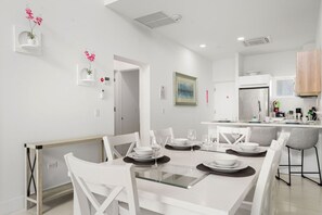A modern kitchen with white cabinets, a built-in oven, and a dining area with a glass table and white chairs. - Charming 2BR Condo w/ Pool Access in Noord, Aruba (Noord)
