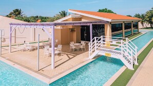 A pool area with a covered seating area, a bridge, and a lifeguard stand. - Charming 2BR Condo w/ Pool Access in Noord, Aruba (Noord)