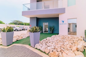 Um edifício moderno com área de recepção, plantas em vasos e entrada ajardinada.
