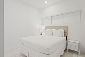 A bedroom with a bed, a nightstand, a lamp, and a radiator. - Charming 2BR Condo w/ Pool Access in Noord, Aruba (Noord)