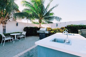 An outdoor kitchen area with a sink, grill, and seating. - Charming 2BR Condo w/ Pool Access in Noord, Aruba (Noord)