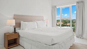 A bedroom with a large bed, two bedside tables, and a view of a landscape through a window.
