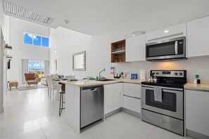 A modern kitchen with a dishwasher, microwave, and oven. - Stunning 2-Bedroom Condo in Noord Aruba (Noord)