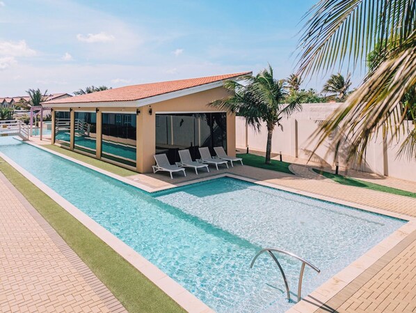 A swimming pool with a covered area and lounge chairs.