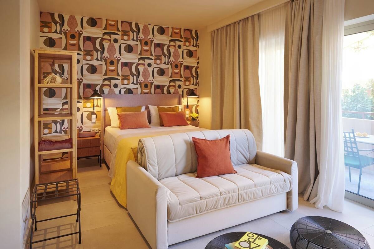 Ein Hotelzimmer mit Bett, Sofa, einem kleinen Tisch und einem Bücherregal.