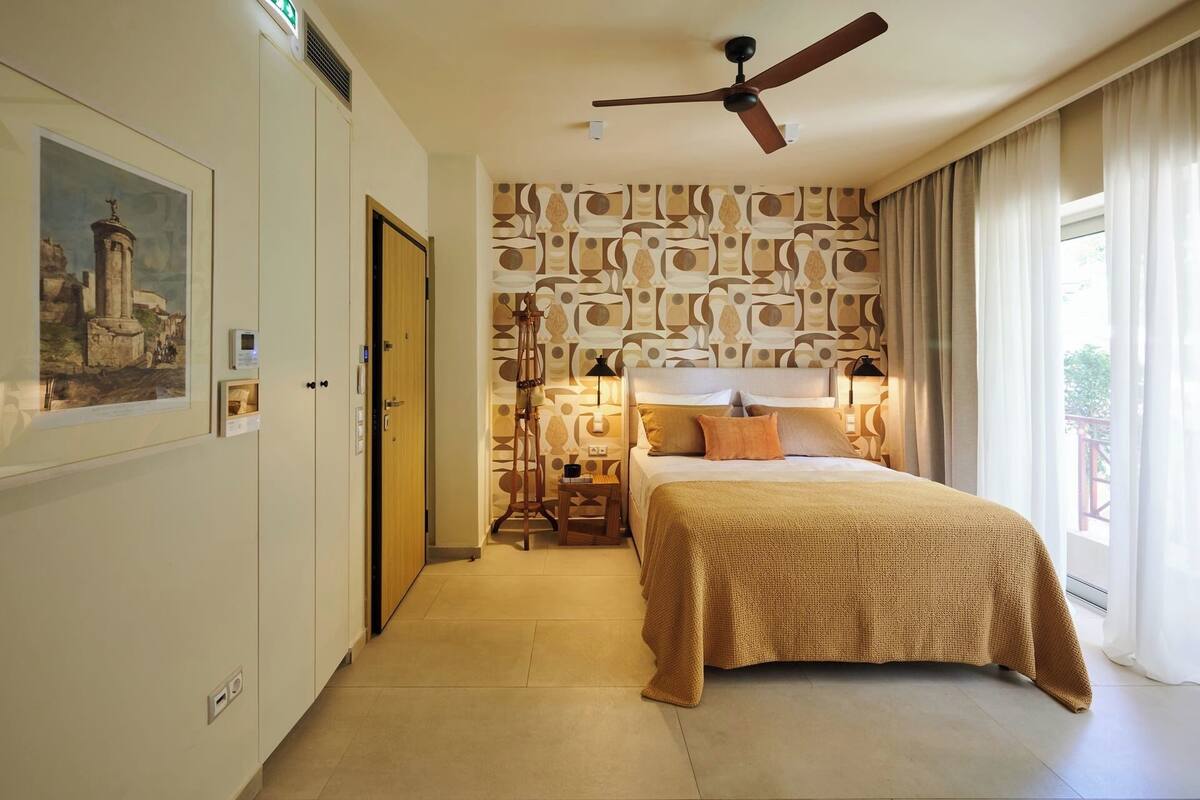 Ein Hotelzimmer mit einem Bett, einem Deckenventilator, einer Wand mit Muster und einem Bild an der Wand.