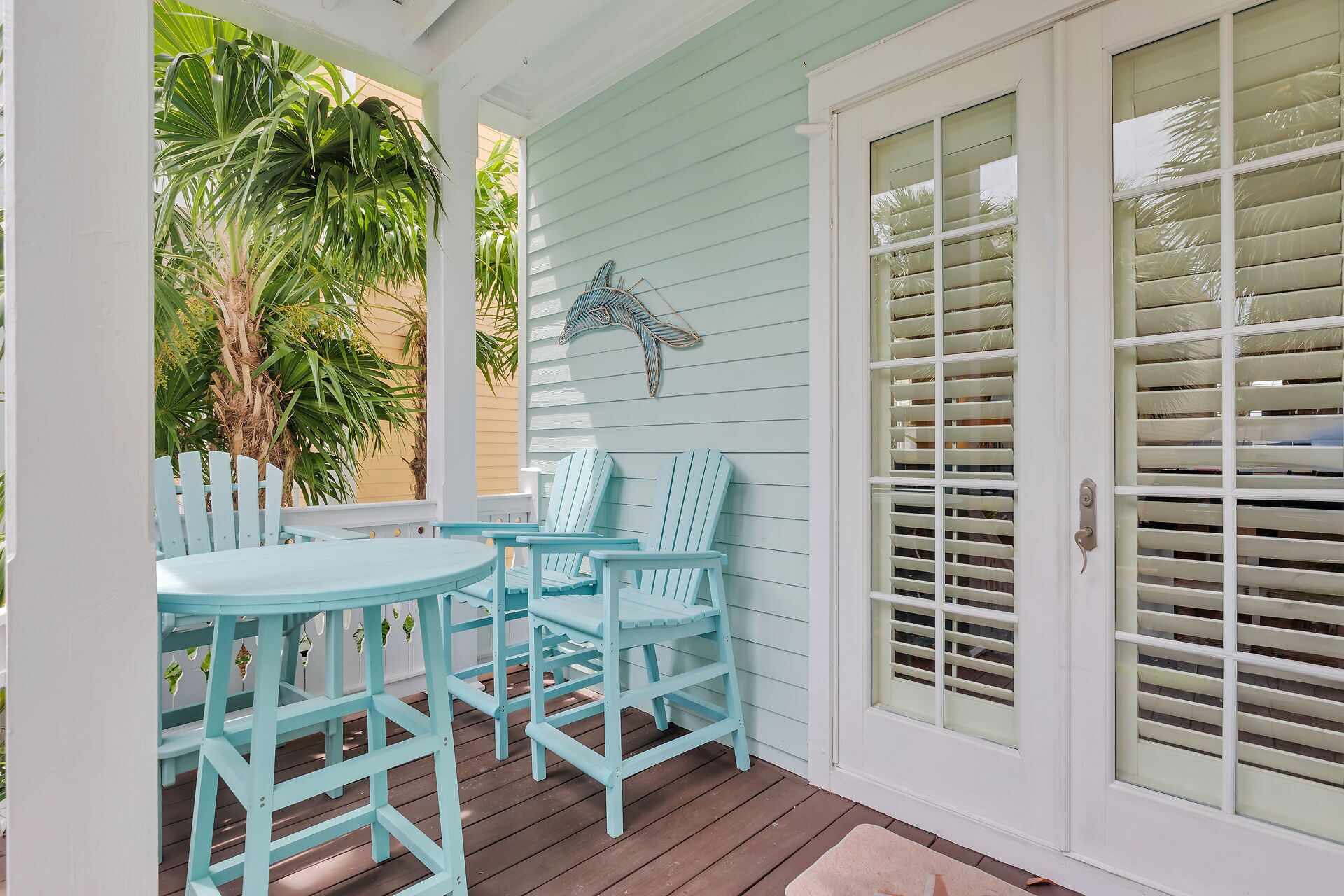 A porch with light blue Adirondack chairs and a small round table.