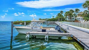 A boat docked at a pier with a clear view of the ocean and a row of houses in the background. - PRIME LOCATION Islamorada Anglers Reef Oceanview Private Beaches, Pool & Marina (Islamorada)