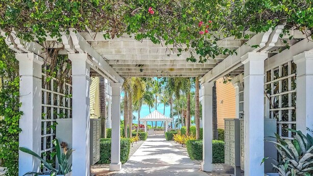 A covered walkway with white columns and a pergola overhead, leading to a building with a blue roof. - PRIME LOCATION Islamorada Anglers Reef Oceanview Private Beaches, Pool & Marina (Islamorada)