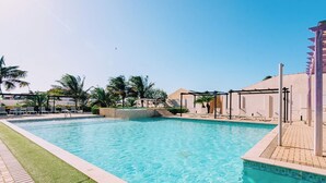 Una piscina con acqua cristallina e azzurra, circondata da palme e sdraio.