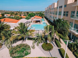 A hotel with a swimming pool, palm trees, and a view of the surrounding area. - Third-Floor 2BR Condo w/ Lap Pool & Gym, Noord (Noord)
