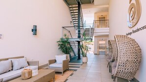 Un interno moderno con una scala, mobili in vimini e un cartello per Heritage Residences.