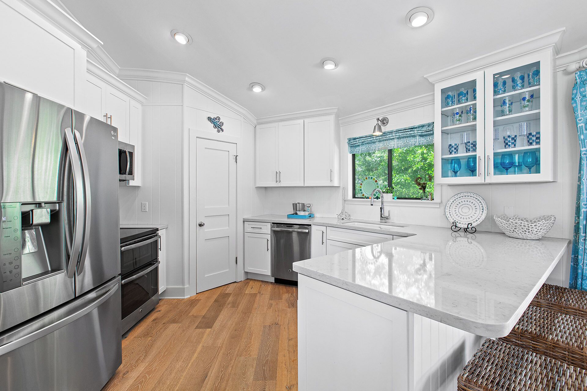 A modern kitchen with white cabinetry, stainless steel appliances, and a large island.