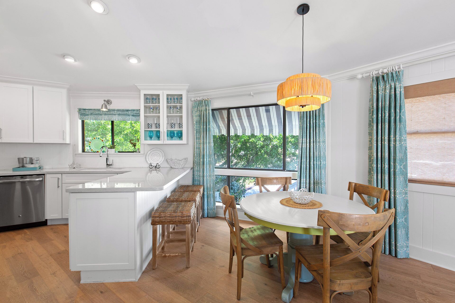 A kitchen with white cabinets, a large island, and a dining area with wooden chairs and a round table.