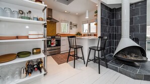 Een moderne keuken met een centraal eiland, zwarte stoelen en een open haard.