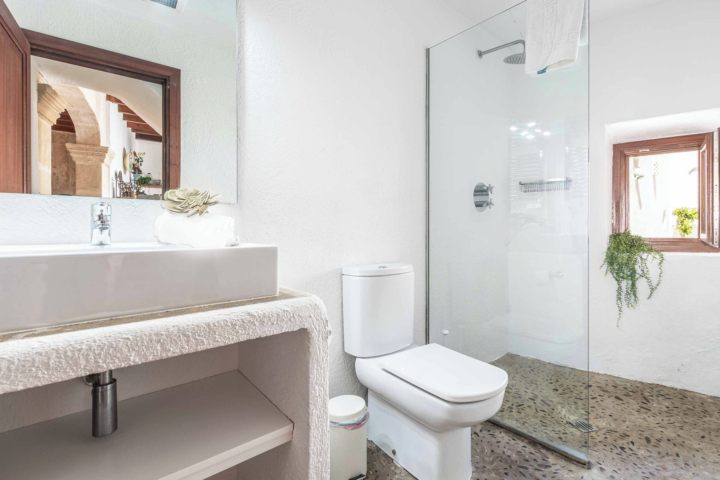 Casa de banho com lavatório, sanita e chuveiro, tudo em branco.