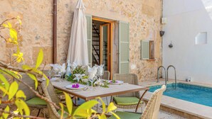A dining area with wicker chairs and a table set for two, overlooking a swimming pool.