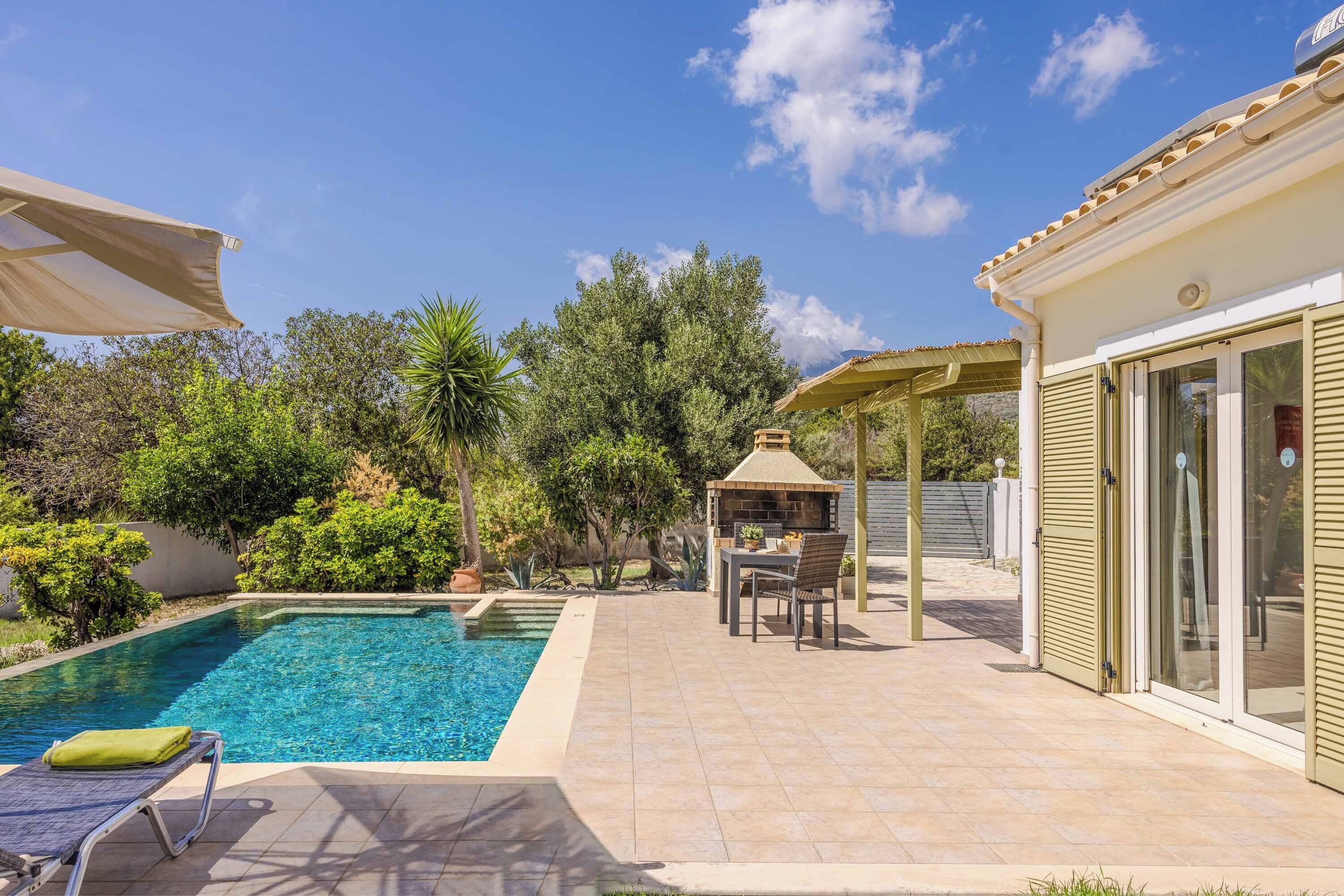 Une piscine avec des chaises longues, un espace barbecue et un patio couvert.