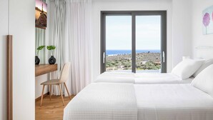 Une chambre avec deux lits, un bureau avec une chaise, une grande fenêtre donnant sur le paysage et un tableau accroché au mur.