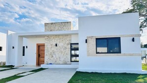 A modern two-story house with a stone facade, a wooden door, and a large window. - Coastal Luxe SOV: 3 Bed, 3.5 Bath, Sosúa Ocean Village (Sosúa)