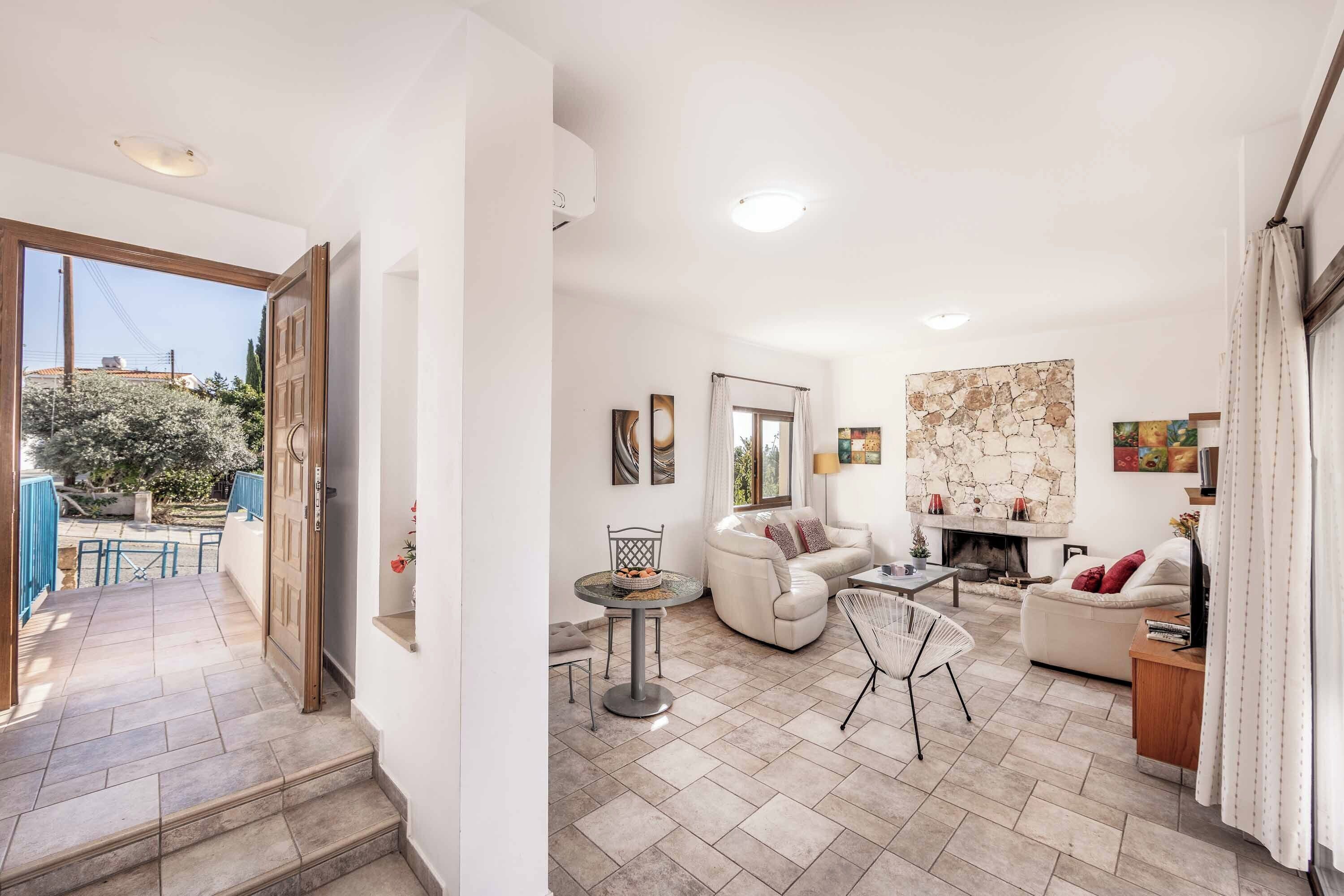 Ein modernes Wohnzimmer mit Kamin, weißen Sofas, einem Esstisch und einer Wand als Steinakzent.