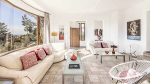 Un salon spacieux avec une grande fenêtre, un canapé, une table basse et un fauteuil.