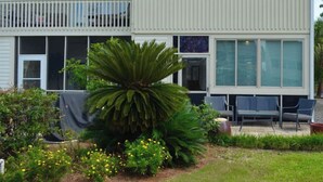 A two-story house with a balcony, large windows, and a covered patio area.