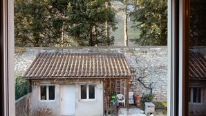 A small house with a tiled roof, a stone wall, and a garden area with a chair and potted plants. - T3 au vert sup downtown Grenoble (Grenoble)
