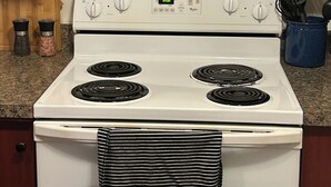 A kitchen with a white stove, four burners, and a digital clock displaying 8:08.