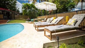 A swimming pool with lounge chairs and an umbrella. - Home with Pool & Pickleball Court near El Yunque (Palma Sola)