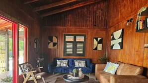 A cozy living room with a wooden interior, a blue sofa, a brown sofa, and a coffee table. - Home with Pool & Pickleball Court near El Yunque (Palma Sola)