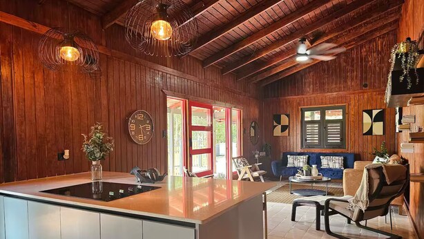 A spacious kitchen with a large island, wooden walls, and a ceiling fan. - Home with Pool & Pickleball Court near El Yunque (Palma Sola)
