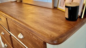 Une commode en bois avec des tiroirs, un miroir et un tableau encadré posé sur le dessus.