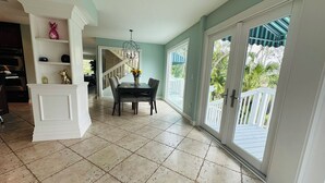 A spacious dining area with a table and chairs, a chandelier, and a view of the outdoors through large sliding glass doors. - LUXURIOUS VILLA WATERFRONT NEAR SIESTA KEY BEACH (Sarasota)