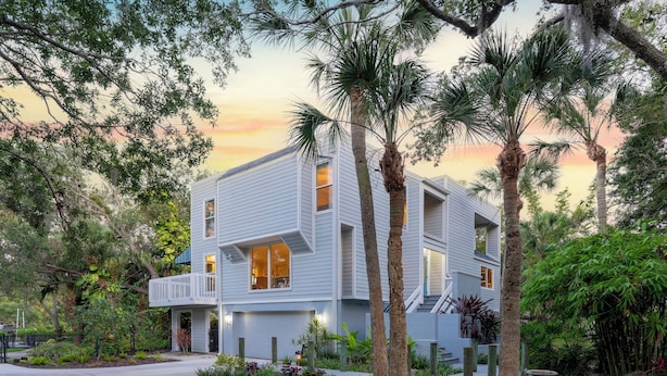 A modern two-story house with a balcony, surrounded by lush greenery and palm trees. - LUXURIOUS VILLA WATERFRONT NEAR SIESTA KEY BEACH (Sarasota)