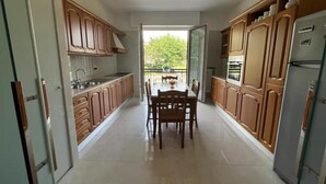 A kitchen with wooden cabinets, a dining table with chairs, and a refrigerator. - Stay overnight in a luxurious apartment, central location within walking distance of the lake (Desenzano del Garda)