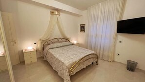 A bedroom with a bed, bedside tables, a TV, and curtains. - Stay overnight in a luxurious apartment, central location within walking distance of the lake (Desenzano del Garda)