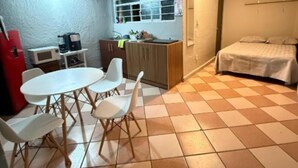 A compact room with a bed, a small kitchenette, a dining table with chairs, and a tiled floor. - Casa Paty! (Oaxaca de Juárez)
