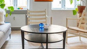 A room with a round table, two chairs, a sofa, and large windows.