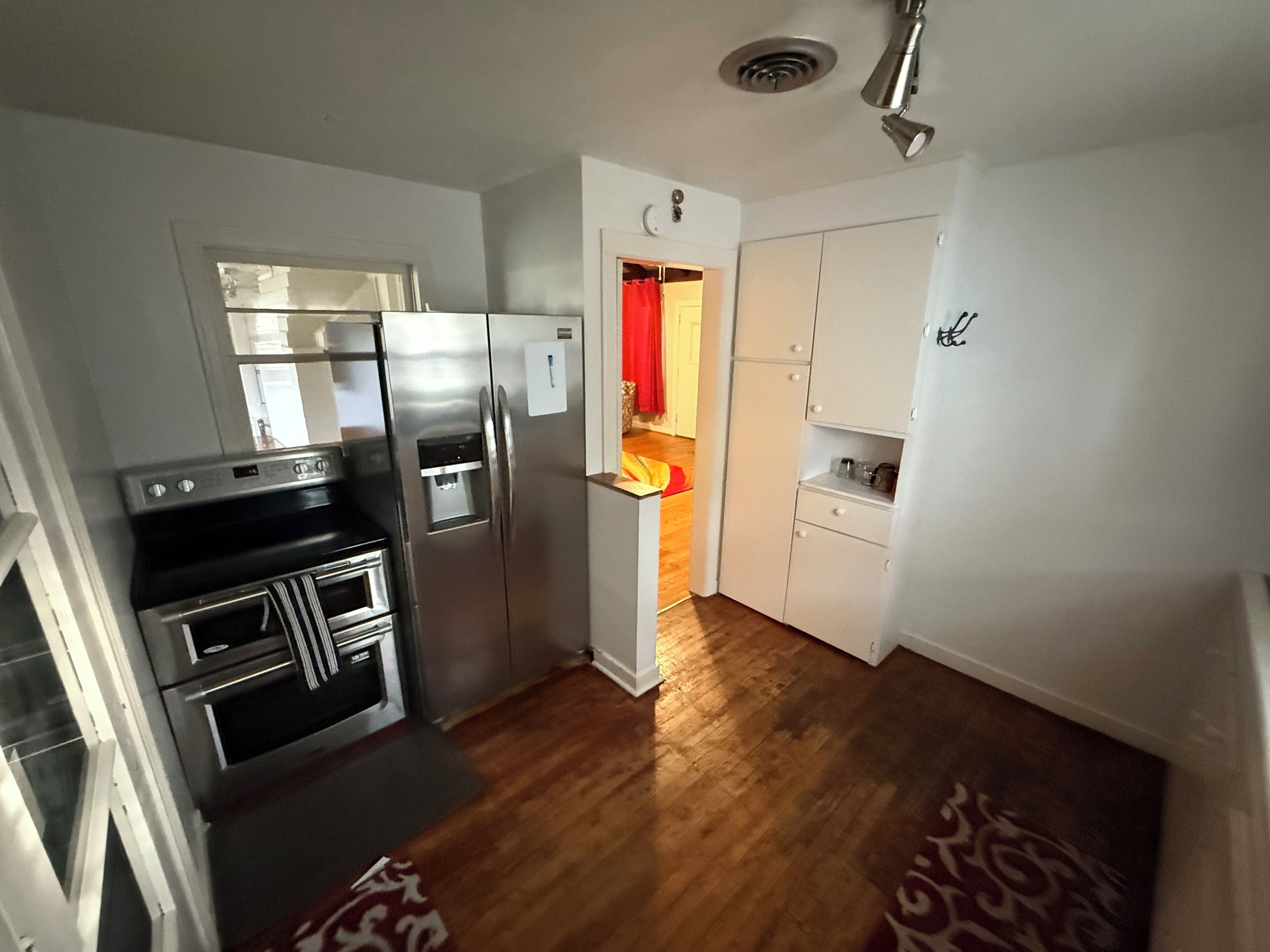 A compact kitchen with stainless steel appliances, a built-in oven, and a water dispenser.
