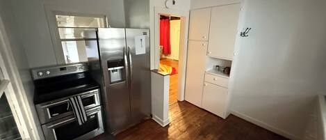 A compact kitchen with stainless steel appliances, a built-in oven, and a water dispenser.